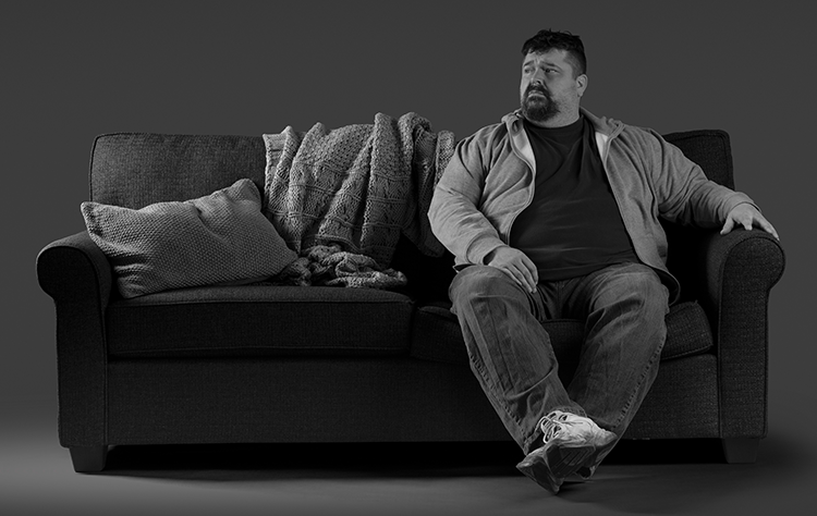Schizophrenia patient Dave with unresolved symptoms sitting on couch.